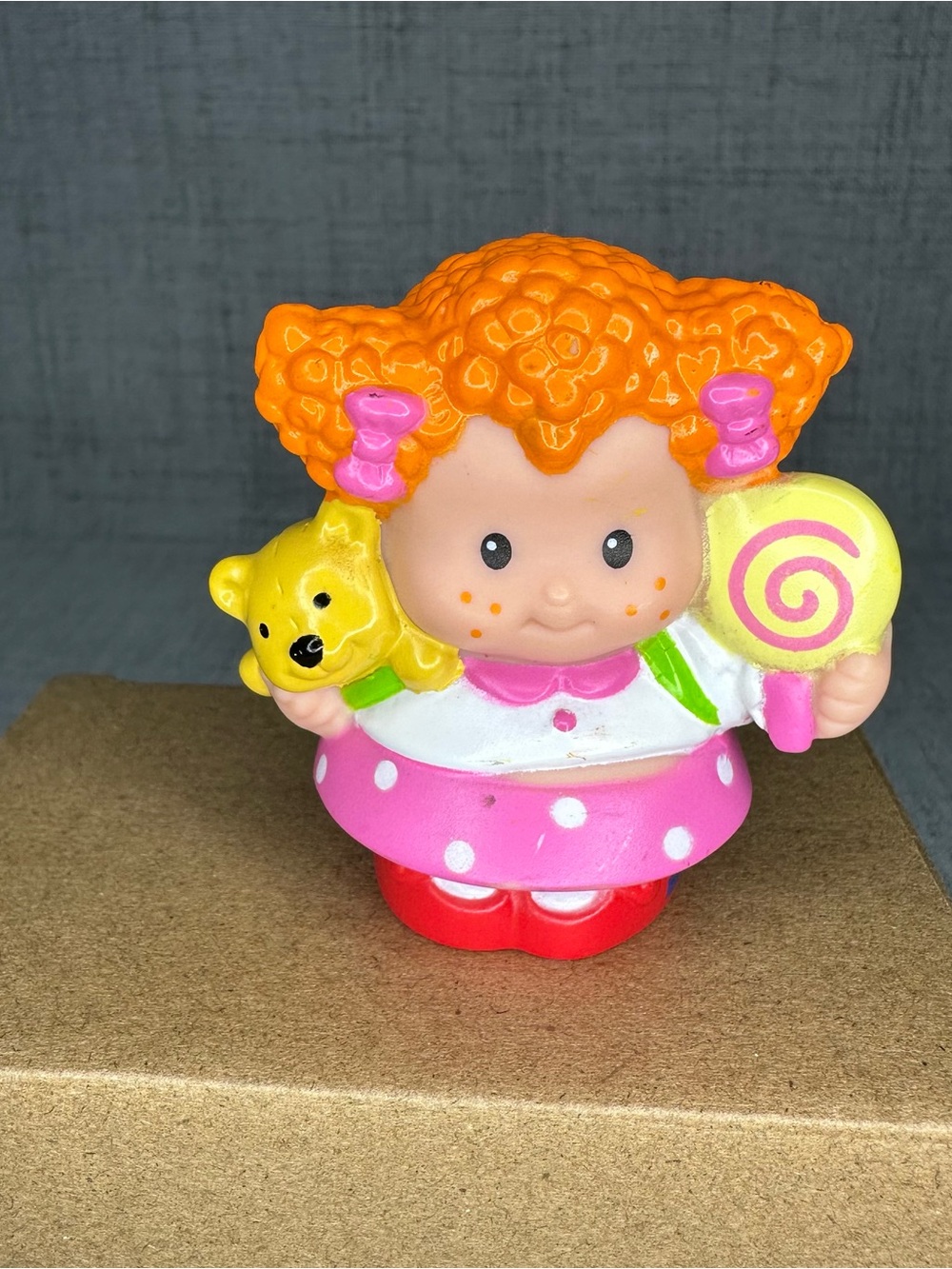 Little people red headed girl holding teddy bear and lollipop